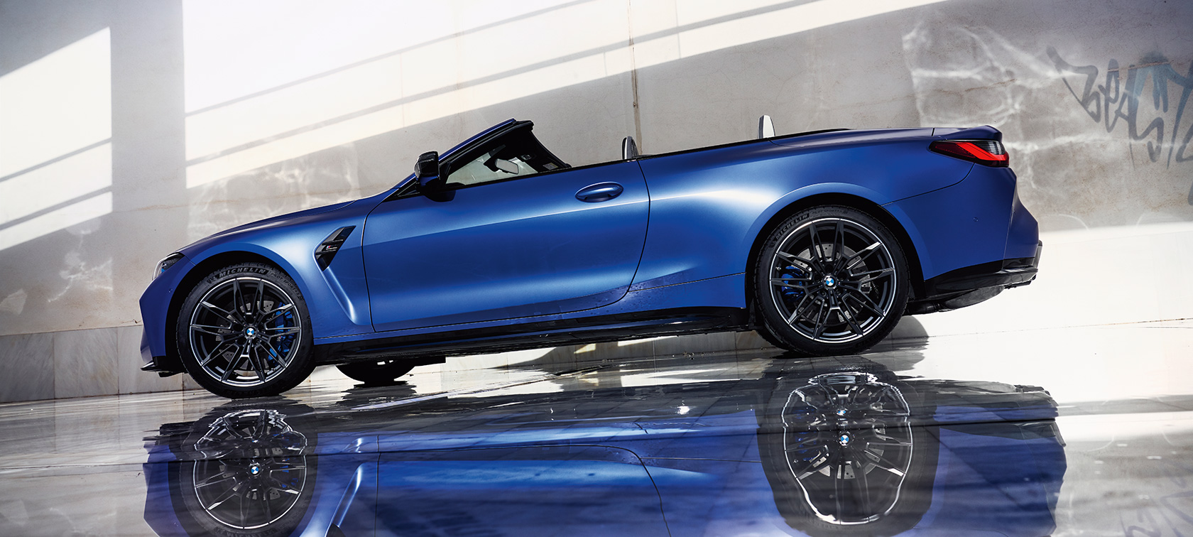 BMW M4 Competition Cabrio s pohonem M xDrive G83 2021 z bočního pohledu od země BMW M4 Competition Cabrio s pohonem M xDrive G83 2021 metalický lak Individual Frozen Portimao Blue (modrá) z bočního pohledu od země