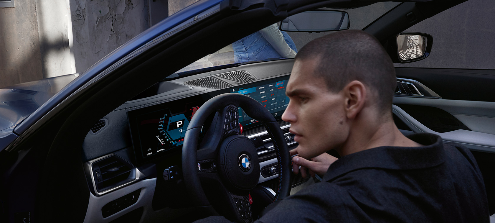 BMW M4 Competition Cabrio s pohonem M xDrive G83 2021 palubní deska BMW M4 Competition Cabrio s pohonem M xDrive G83 2021 metalický lak Individual Frozen Portimao Blue (modrá) palubní deska s otevřenými dveřmi a mužským modelem