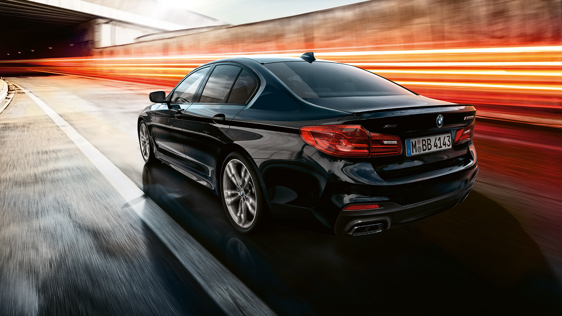 Jízdní dynamika. BMW M550i a BMW M550d za jízdy při pohledu zezadu ze tří čtvrtin.