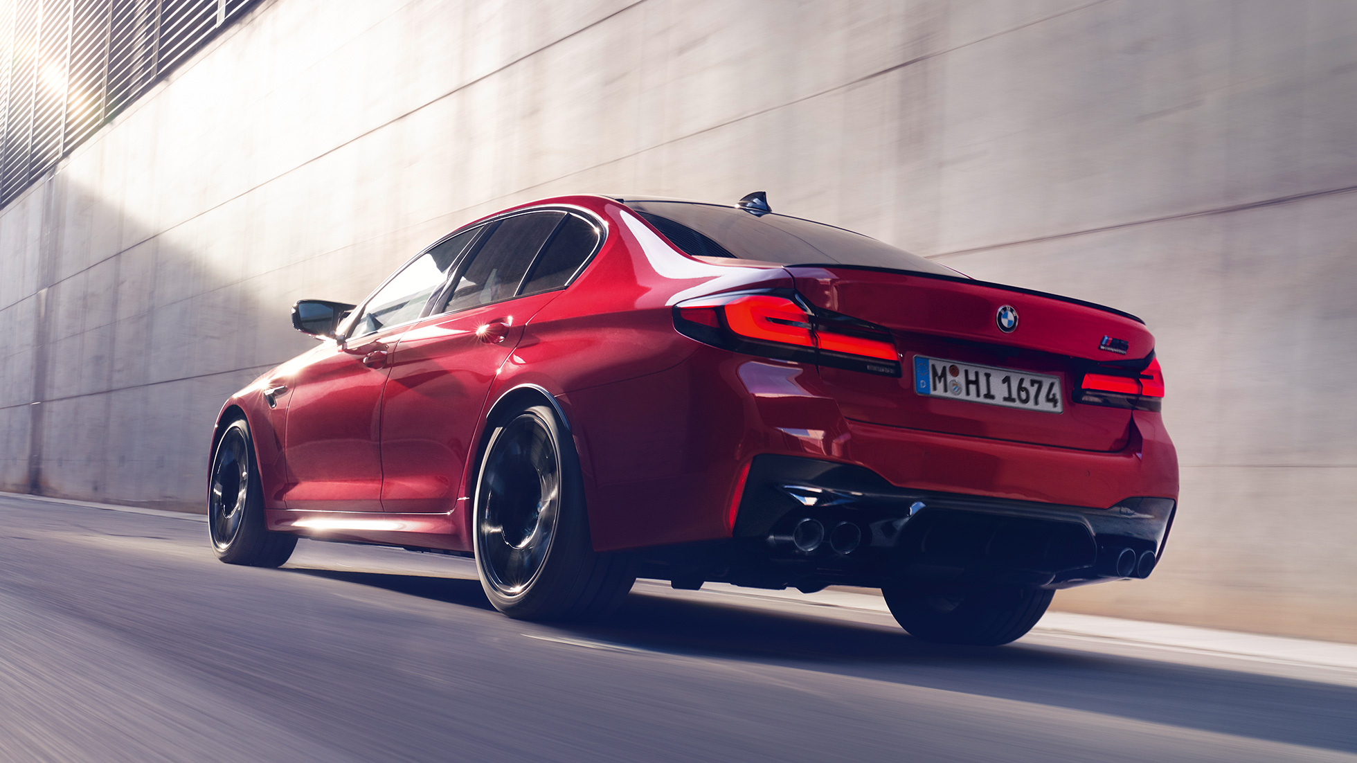BMW M5 Competition F90 LCI Facelift 2020 tříčtvrteční pohled zezadu BMW M5 Competition F90 LCI Facelift 2020 v barvě BMW Invidividual Imola Red (červená) z tříčtvrtečního pohledu zezadu při jízdě