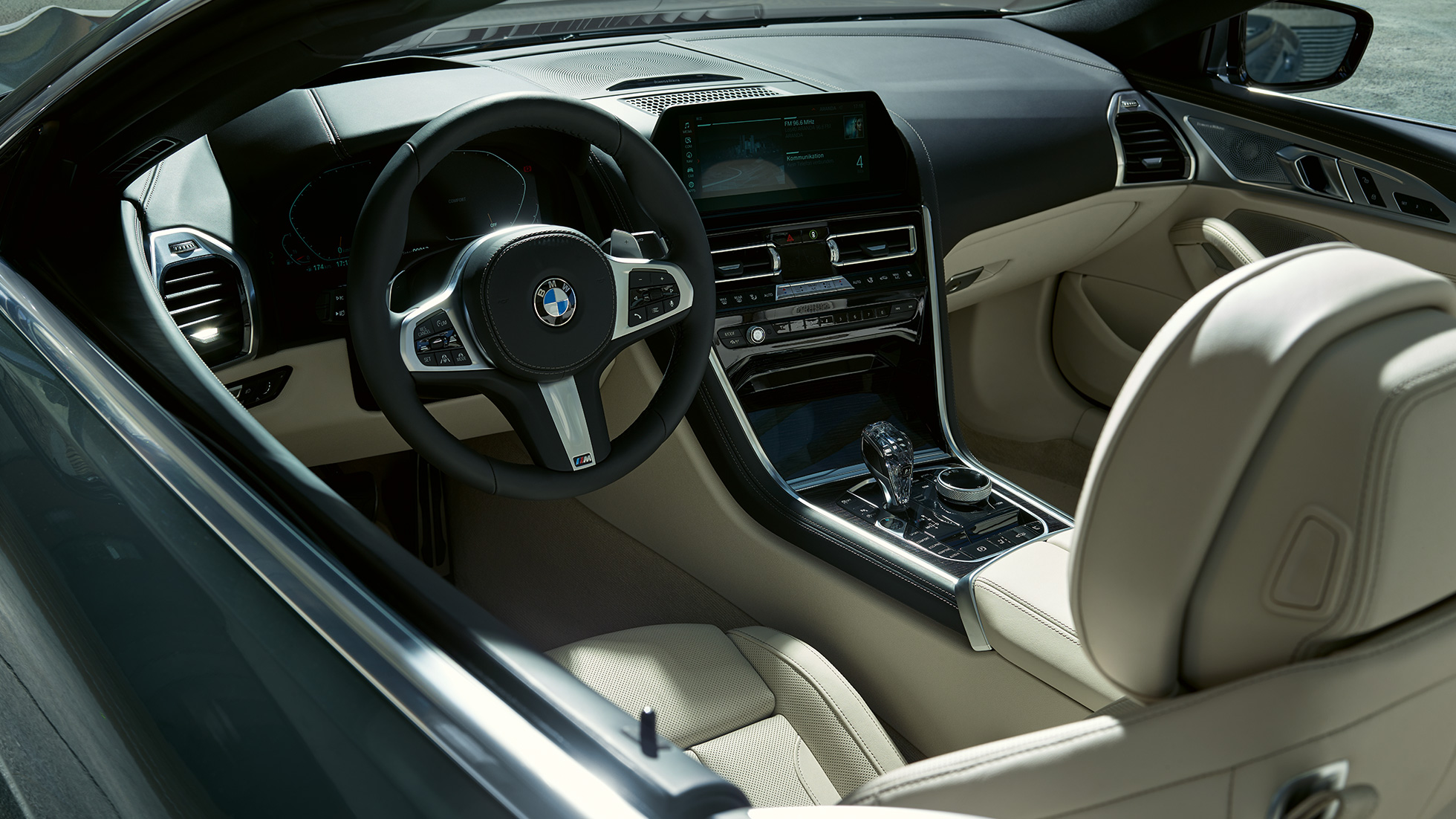 BMW M850i xDrive Cabrio, kokpit. BMW M850i xDrive Cabrio v šedé barvě Dravit Grey se staženou střechou, kokpit s M koženým volantem.