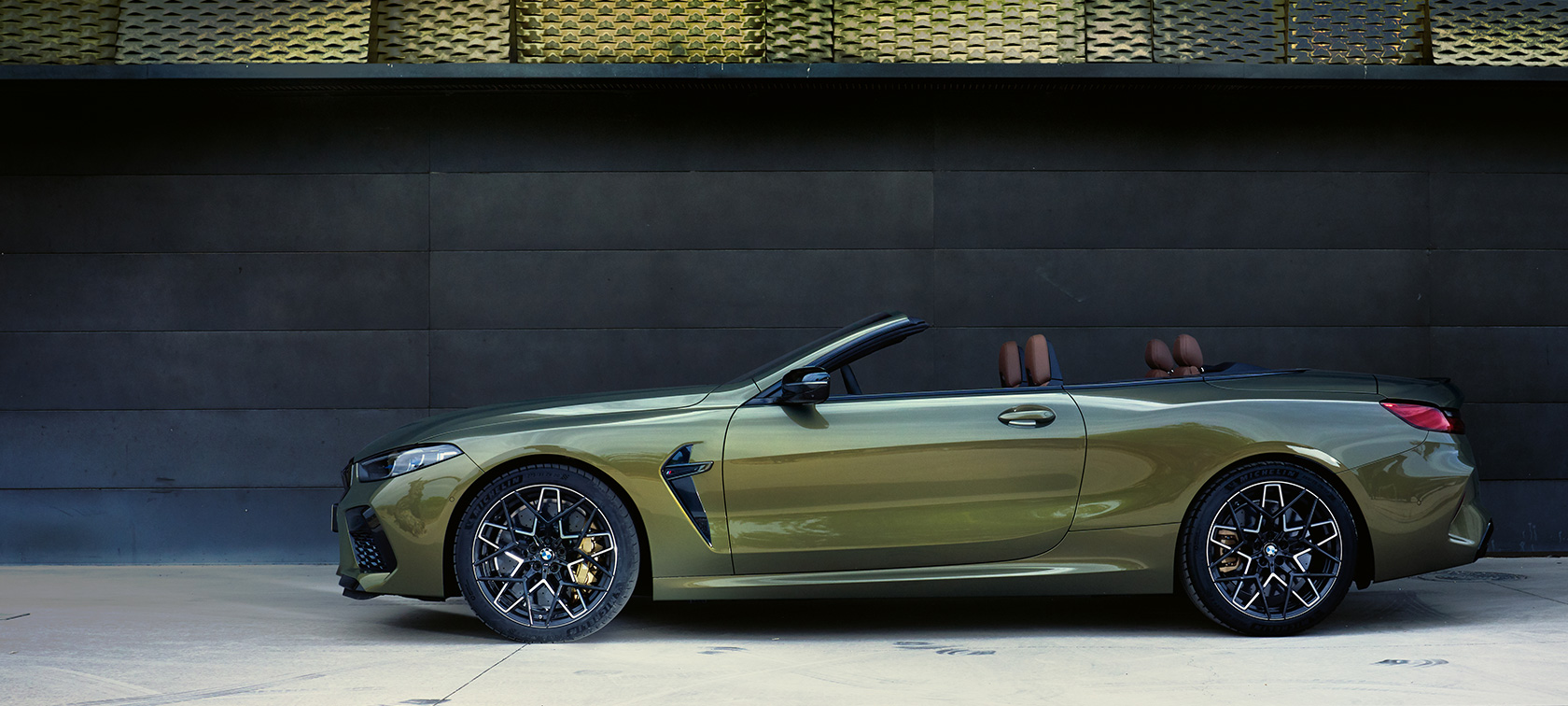 BMW M8 Competition Cabrio F91 LCI Facelift 2022 statický pohled z boku BMW XM8 Competition Cabrio F91 LCI Facelift 2022 metalický lak BMW Individual Brass (zelená) pohled z boku s otevřenými dveřmi a ženským modelem