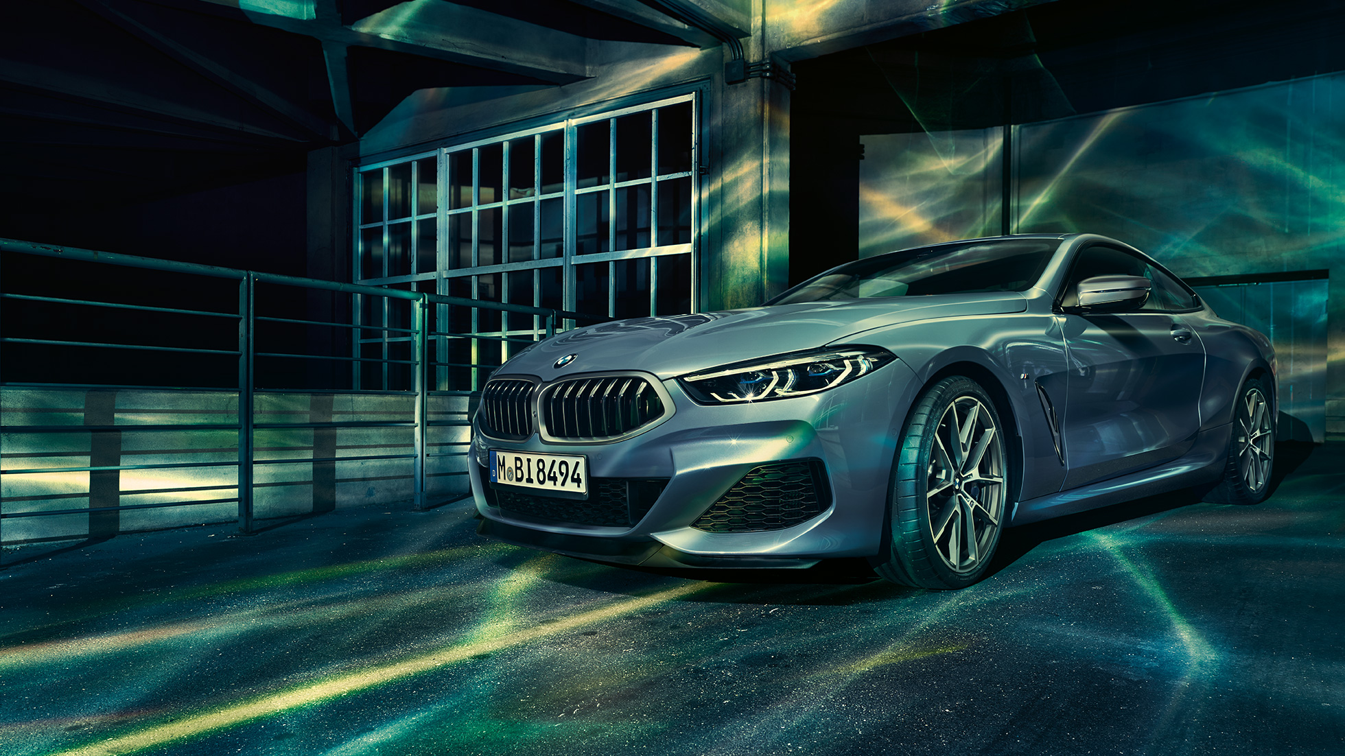 BMW M850i xDrive Coupé, tříčtvrteční pohled zpředu. BMW M850i xDrive Coupé v metalické barvě Barcelona Blue, tříčtvrteční pohled zpředu, stojící před budovou.
