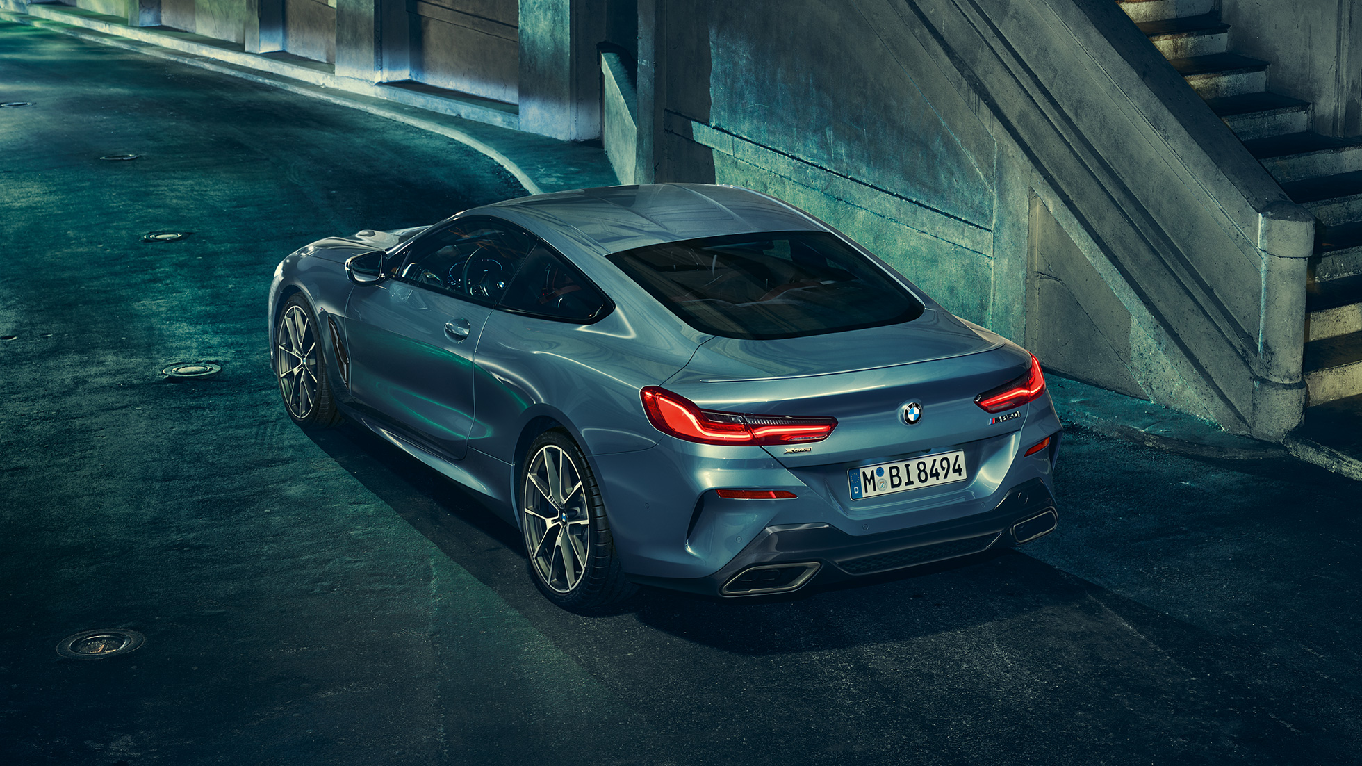 BMW M850i xDrive Coupé, tříčtvrteční pohled zleva. BMW M850i xDrive Coupé v metalické barvě Barcelona Blue, tříčtvrteční pohled zleva, staticky v noci.