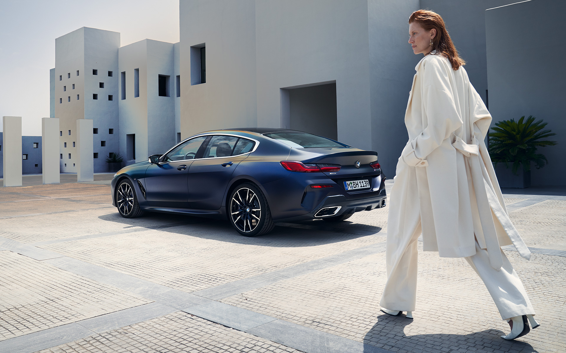BMW M850i xDrive Gran Coupé G16 LCI Facelift 2022 pohled z boku s modelkou BMW M850i xDrive Gran Coupé G16 LCI Facelift v metalické barvě 2022 BMW Invidividual Frozen Tanzanite Blue (modrá) ze tříčtvrtečního pohledu zezadu s modelkou