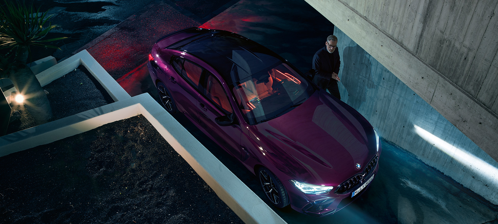 BMW M8 Competition Gran Coupé z ptačí perspektivy BMW M8 Competition Gran Coupé F93 2020 v metalické barvě BMW Individual Ametrine z tříčtvrtečního pohledu, stojící před budovou z ptačí perspektivy