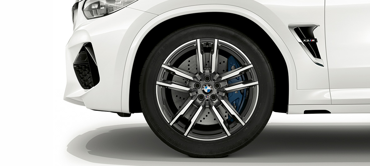 BMW X3 M, 21palcová M kola z lehké slitiny v šedém provedení Orbit Grey. BMW X3 M v bílé barvě Alpine White, 20palcová M kola z lehké slitiny v šedém provedení Orbit Grey.