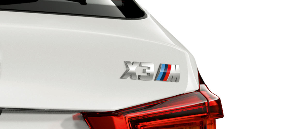 BMW X3 M, označení modelu. BMW X3 M v bílé barvě Alpine White, exteriér, zadní část s označením modelu.
