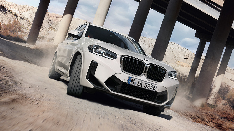 BMW X3 M F97 LCI Facelift 2021 v barvě Alpine White (bílá) M tříčtvrteční pohled zepředu při jízdě zatáčkou