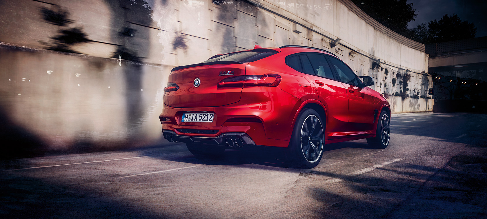 BMW X4 M Competition, tříčtvrteční pohled zezadu. BMW X4 M Competition v červené metalické barvě Toronto Red, jízdní, exteriér, tříčtvrteční pohled zezadu.