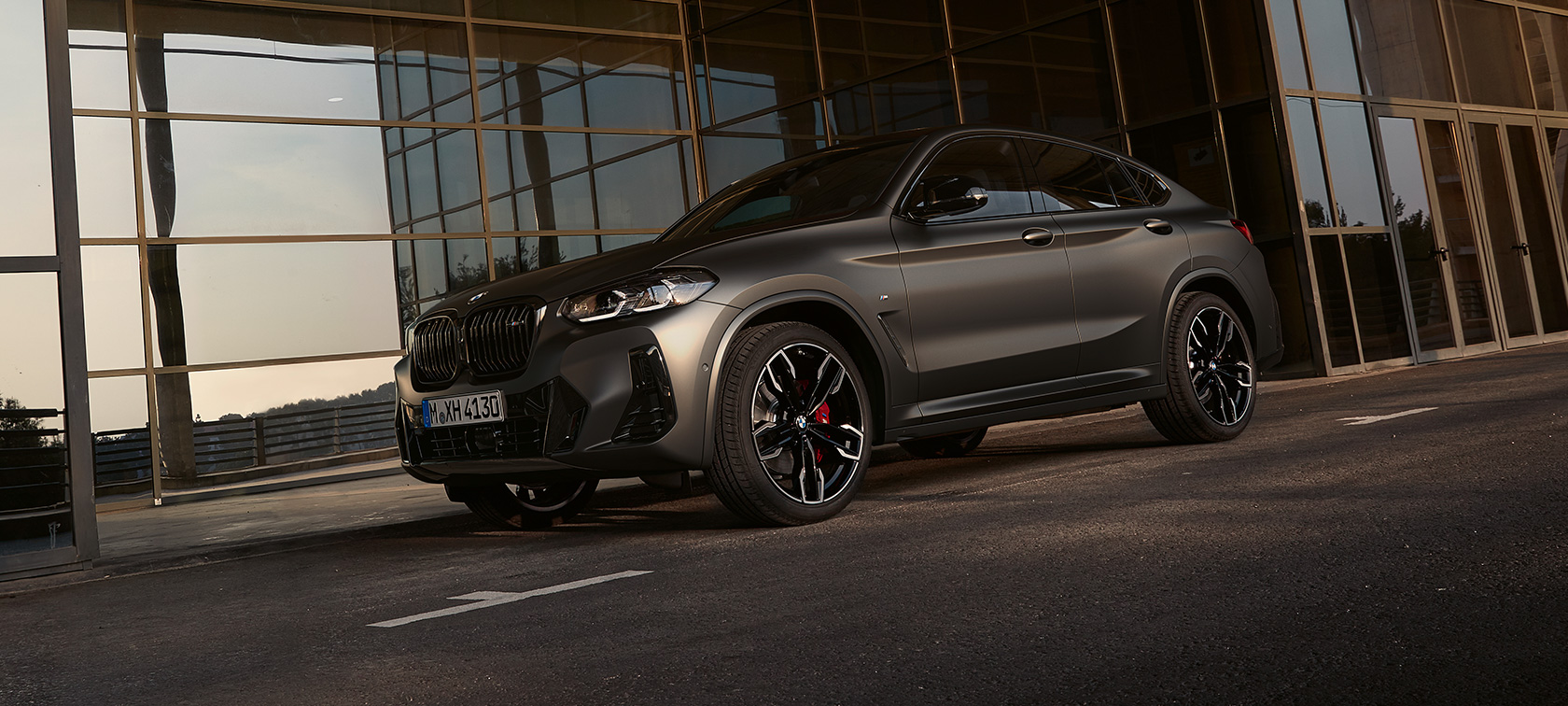Tříčtvrteční pohled zepředu BMW X4 M40i G02 LCI 2021 Facelift BMW X4 M40i G02 LCI 2021 Facelift tříčtvrteční pohled zepředu před skleněnou stěnou