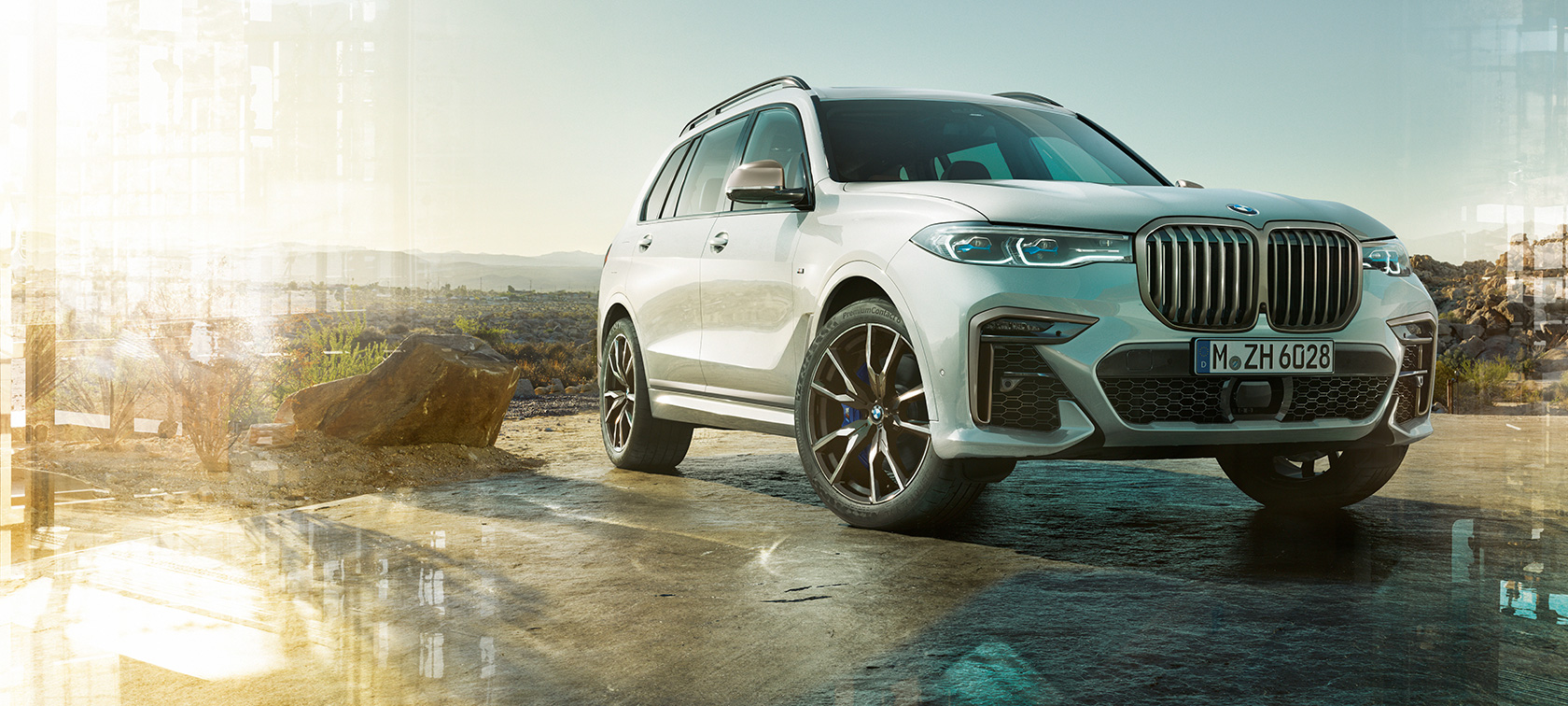M automobil BMW X7, tříčtvrteční přední pohled z levé strany M automobil BMW X7 v bílé barvě Mineral White, stojící, tříčtvrteční přední pohled z levé strany