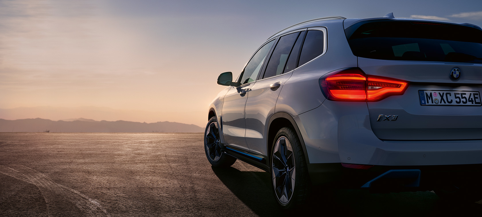 BMW iX3 G08 stojící na ulici BMW iX3 G08 2020 v metalické barvě Mineral White (bílá) z tříčtvrtečního pohledu zezadu stojící na ulici