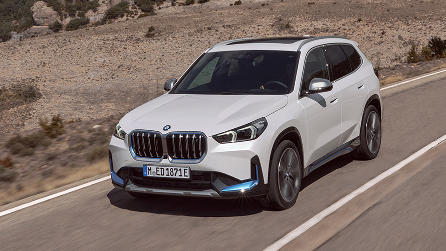 BMW iX1 U11 první generace, jízdní tříčtvrteční záběr zepředu na silnici BMW X modely BMW iX1 U11 první generace, jízdní tříčtvrteční záběr zepředu na silnici