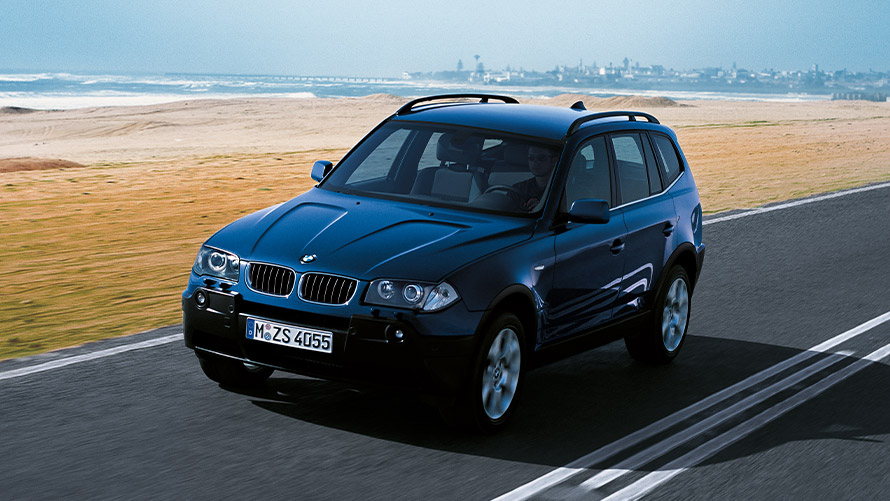 BMW X3 E83 první generace, tříčtvrteční jízdní záběr zepředu na silnici BMW řady X BMW X3 E83 první generace, tříčtvrteční jízdní záběr zepředu na silnici