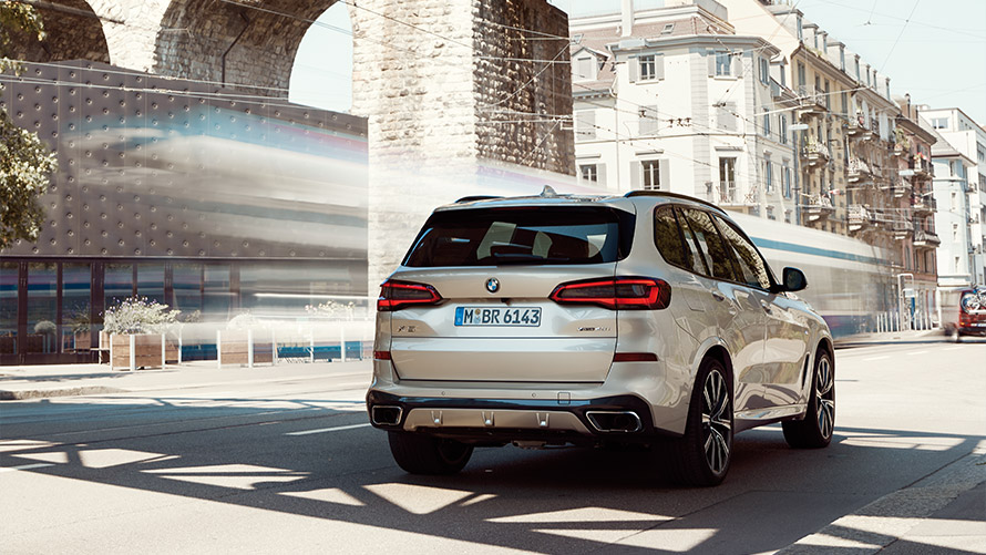 BMW X5 G05 čtvrtá generace, tříčtvrteční statický záběr zezadu před budovou BMW řady X BMW X5 G05 čtvrtá generace, tříčtvrteční statický záběr zezadu před budovou