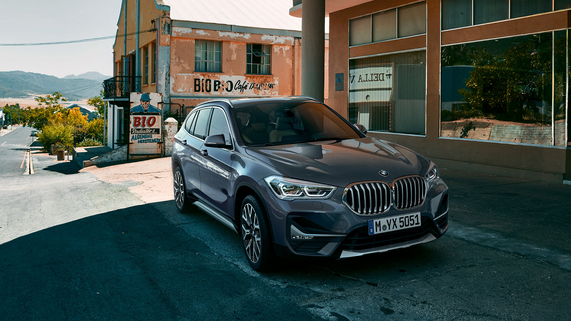 BMW X1, tříčtvrteční pohled zepředu. BMW X1, tříčtvrteční pohled zepředu na vůz stojící před městskou scenérií.