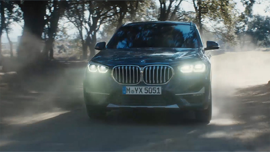 BMW X1 F48 LCI tříčtvrteční pohled zepředu BMW X1 F48 LCI tříčtvrteční jízdní záběr zepředu před přírodní scenérií