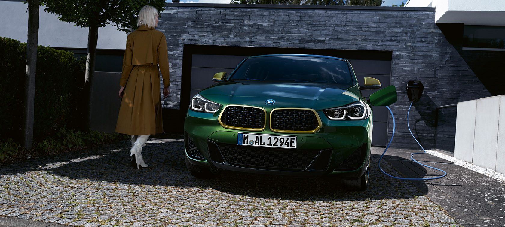 Pohled zepředu BMW X2 F39 2020 metalický lak Sanremo Green (zelená) Pohled zepředu při nabíjení s modelem na levé straně BMW X2 F39 metalický lak Sanremo Green (zelená)