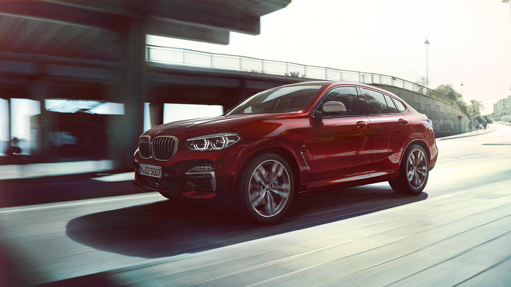 Dynamická příď BMW X4. BMW X4 M40i G02 2018 v metalické barvě Flamenco Red (červená) se zářivým efektem ze tříčtvrtečního pohledu zpředu