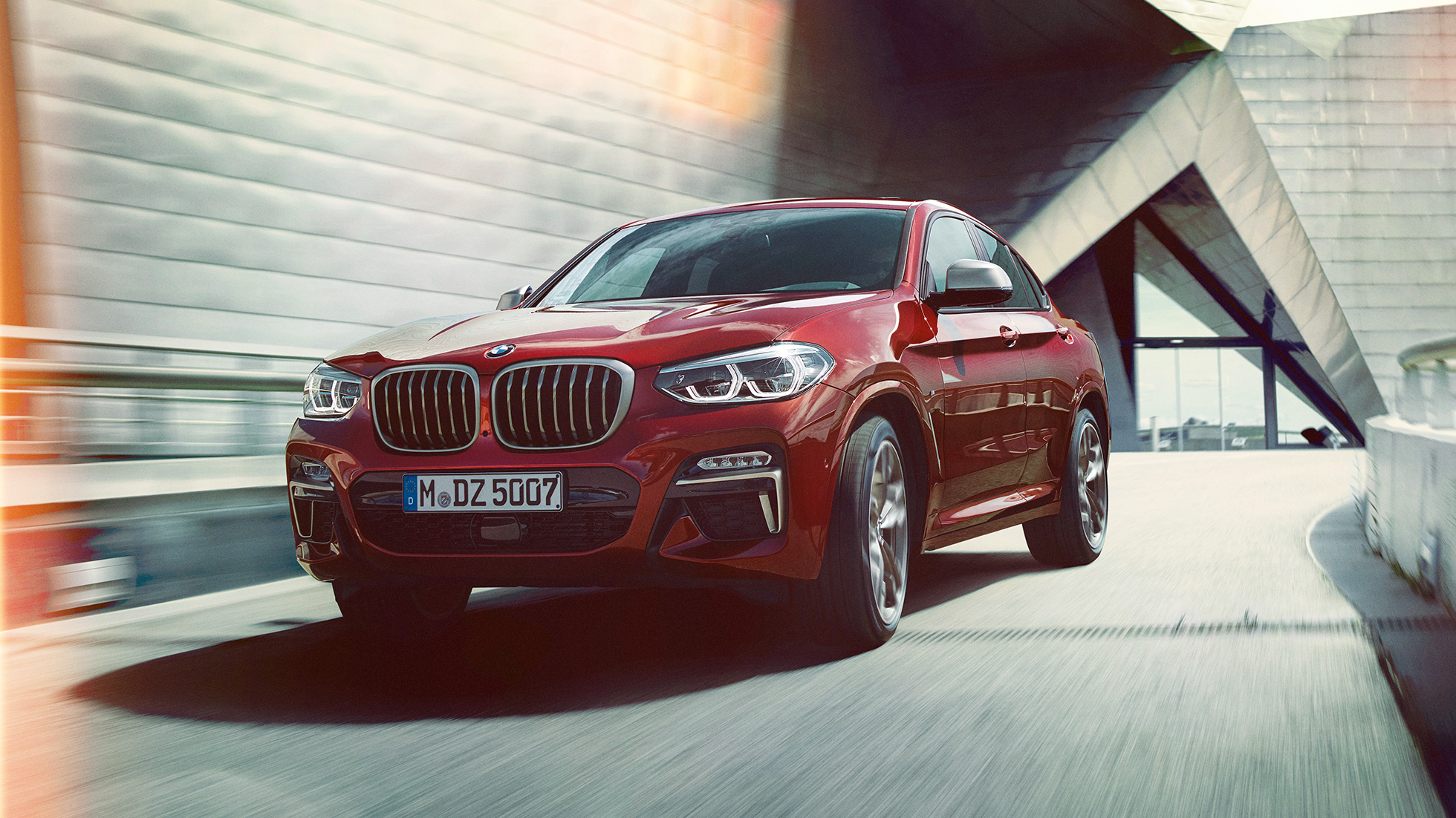 Tříčtvrteční pohled zepředu BMW X4 BMW X4 M40i G02 2018 v metalické barvě Flamenco Red (červená) se zářivým efektem ze tříčtvrtečního pohledu zpředu