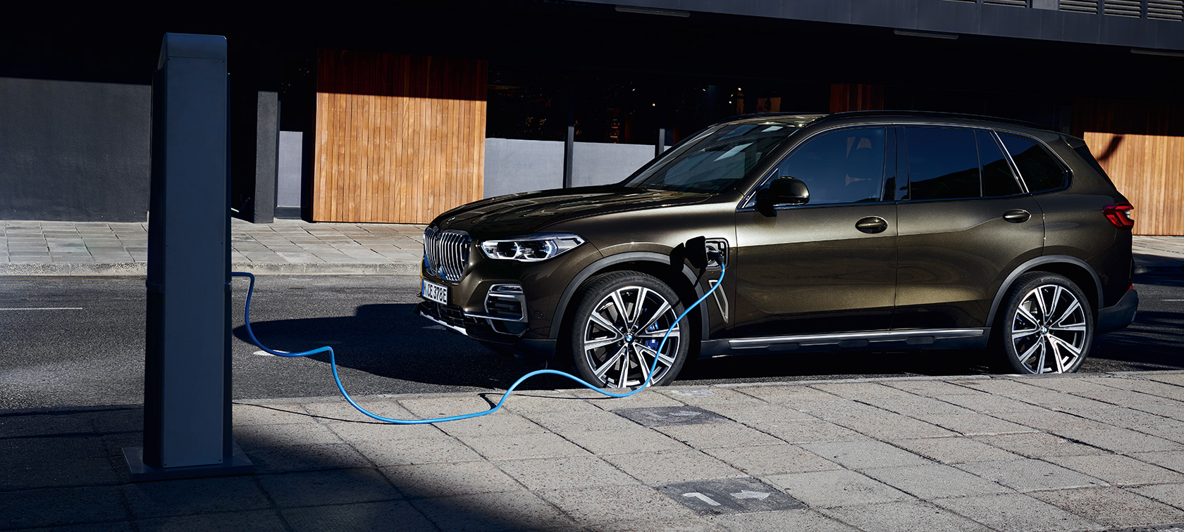 Plug-in hybridní BMW X5 xDrive45e G05 tříčtvrteční pohled z boku Plug-in hybridní BMW X5 xDrive45e G05 tříčtvrteční pohled z boku při nabíjení