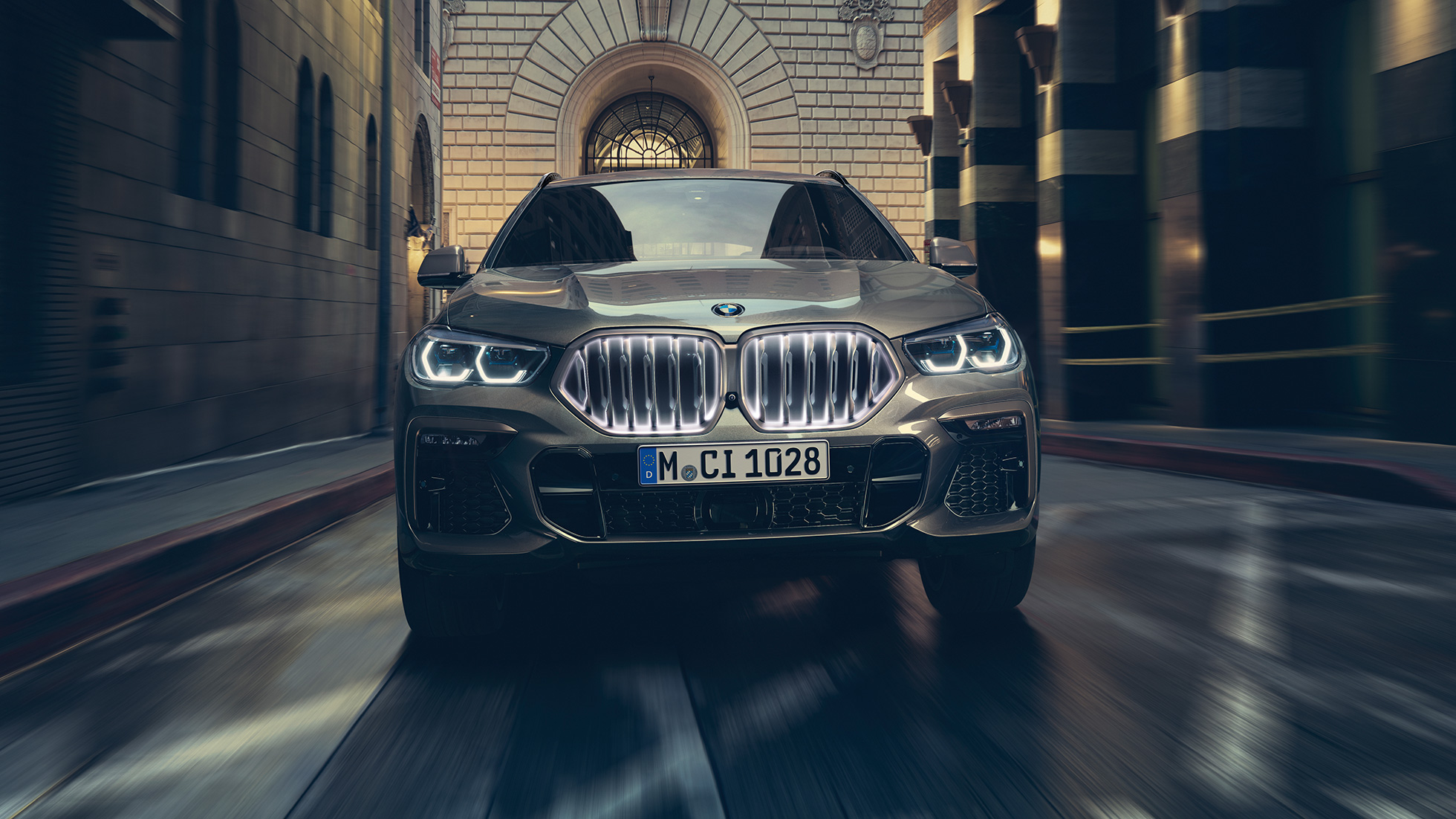 BMW X6 s BMW maskou chladiče ve tvaru ledvinek Iconic Glow Pohled zepředu na BMW X6 v městském prostředí.