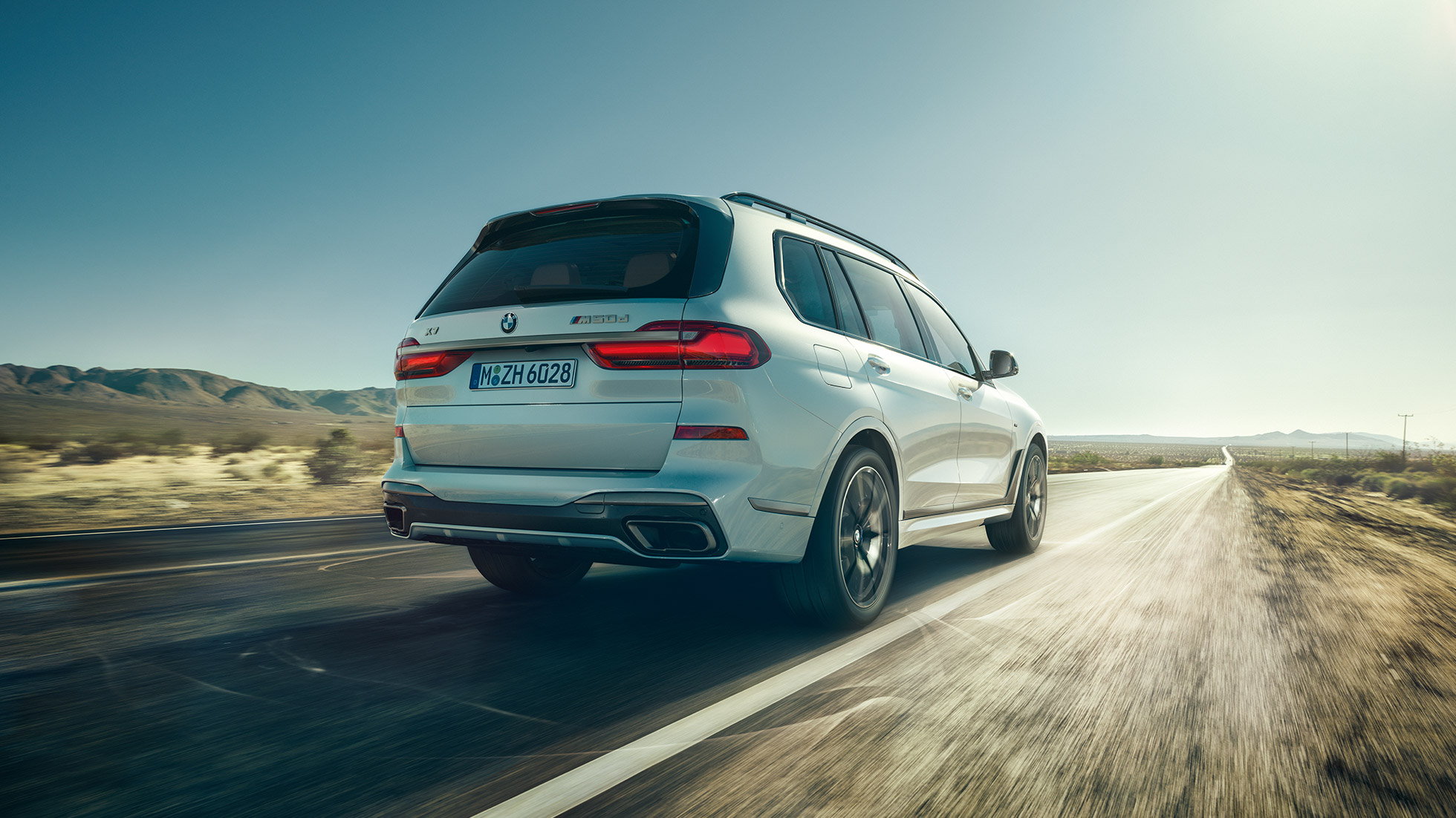 BMW X7 M50d, záběr zezadu BMW X7 M50d: jedoucí bílý BMW X7 zezadu