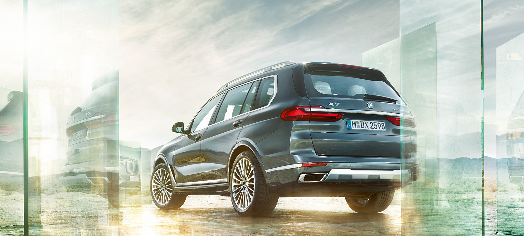 BMW X7, tříčtvrteční pohled zezadu BMW X7 v barvě Arctic Grey ze tříčtvrtečního pohledu zezadu před pouštní krajinou, G07 2019