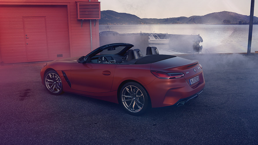 Zadní pohled na oranžové BMW Z4 First Edition Zadní pohled na oranžové BMW Z4 First Edition před červeným domem na pobřeží