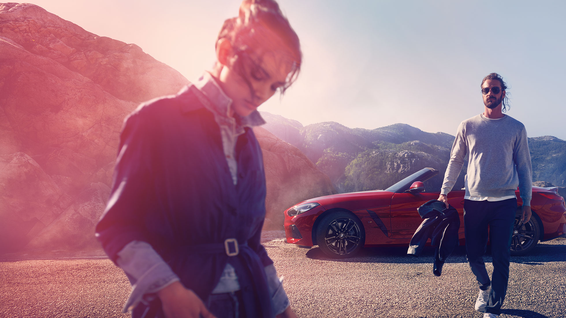 BMW Z4 Roadster stojící před horským hřebenem Muž, žena a BMW Z4 Roadster stojící před horským hřebenem