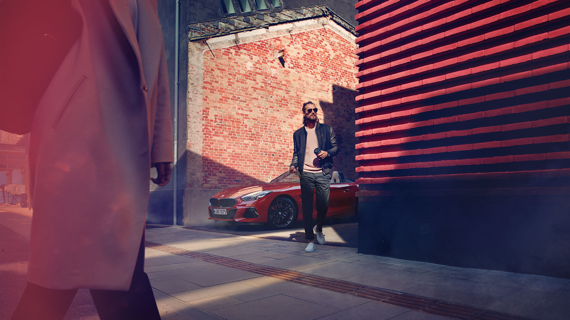 BMW Z4 Roadster v boční ulici Muž v boční ulici stojící před BMW Z4 Roadster v boční ulici
