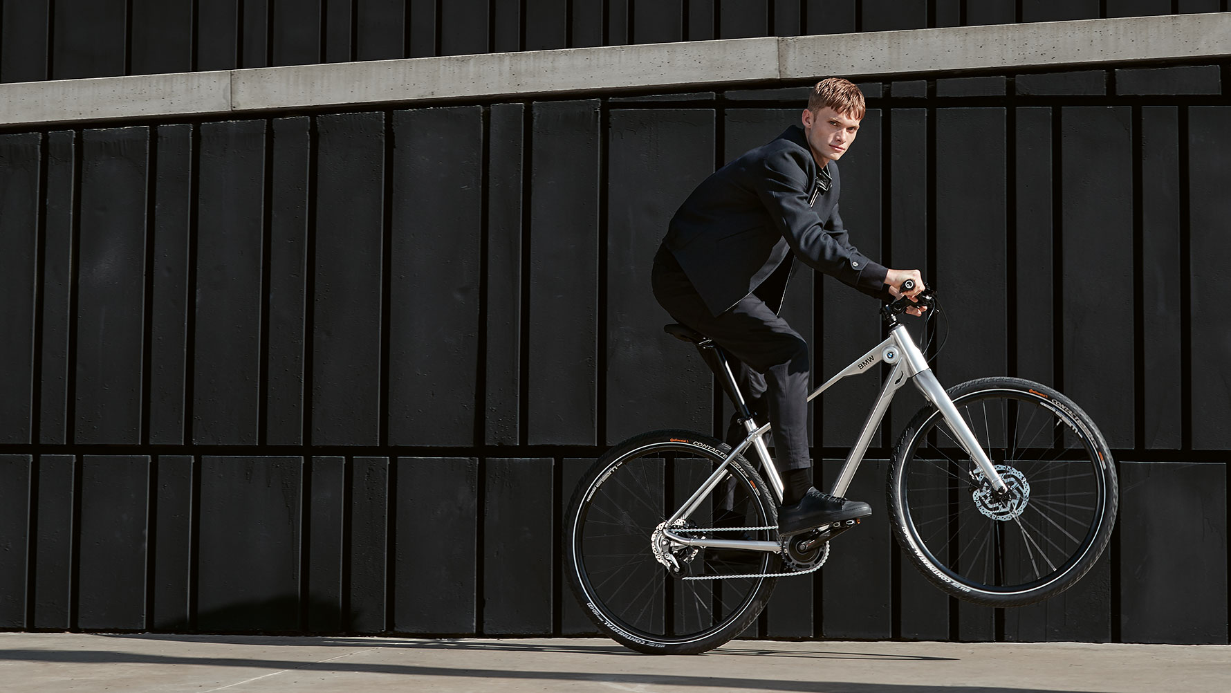 Na obrázku je mladý muž předvádějící dynamickou „jízdu po zadním“ na kole BMW Cruise Bike. Na obrázku je mladý muž předvádějící dynamickou „jízdu po zadním“ na kole BMW Cruise Bike.