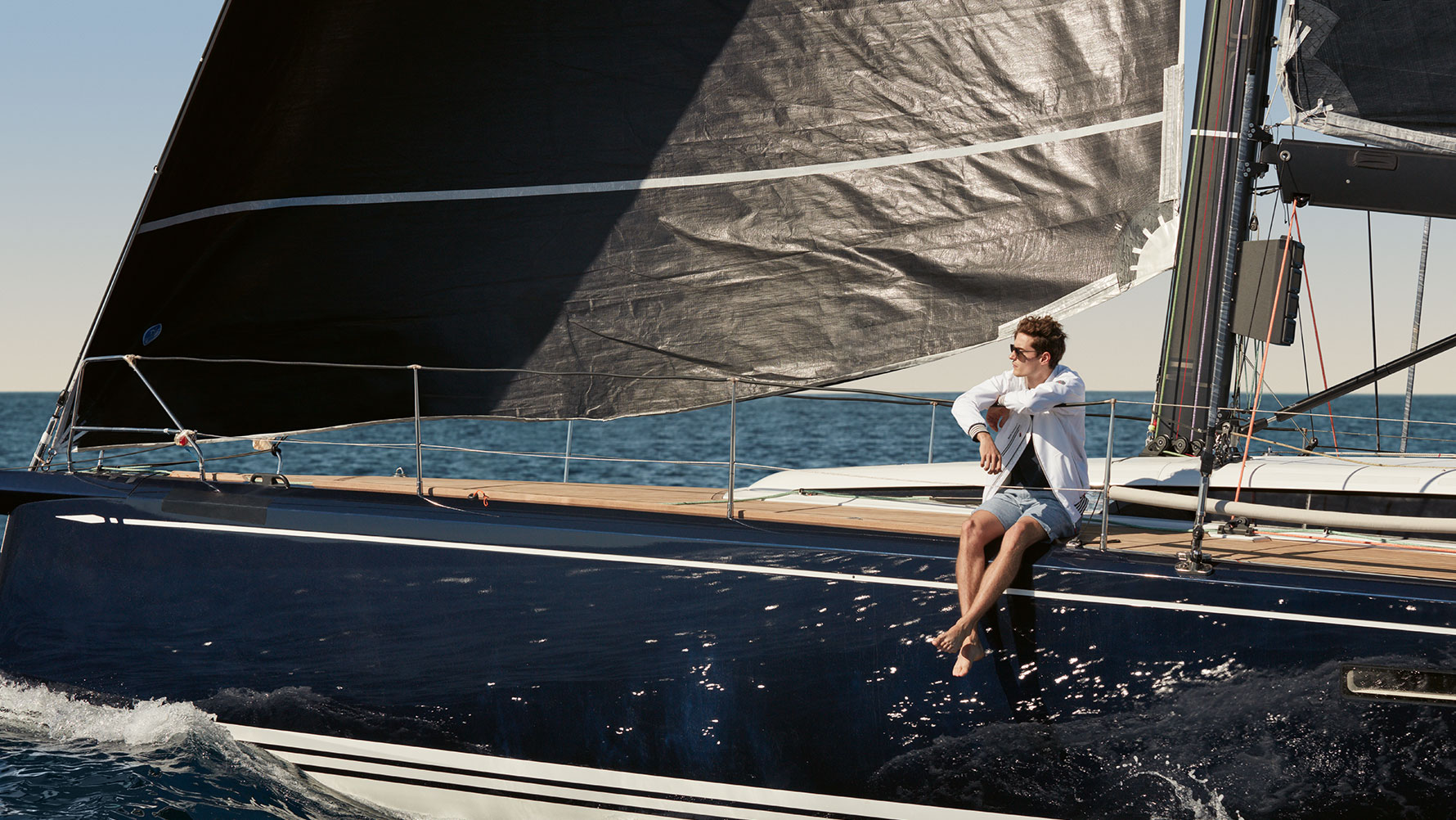 Muž sedící na jachtě má na sobě pánskou bundu BMW Yachtsport z kolekce BMW Yachtsport. Muž sedící na jachtě má na sobě pánskou bundu BMW Yachtsport z kolekce BMW Yachtsport.