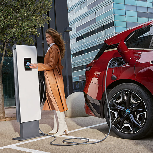 BMW iX i20 u nabíjecí stanice Žena s nabíjecí kartou BMW Charging Card