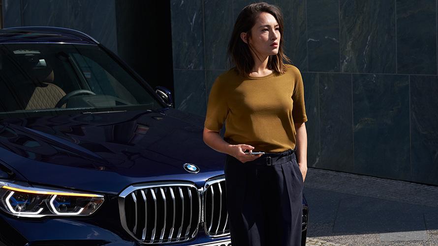 Asistenční služba & asistence v případě poruchy Žena sedí před jejím BMW a používá Asistenční služba & asistence v případě poruchy