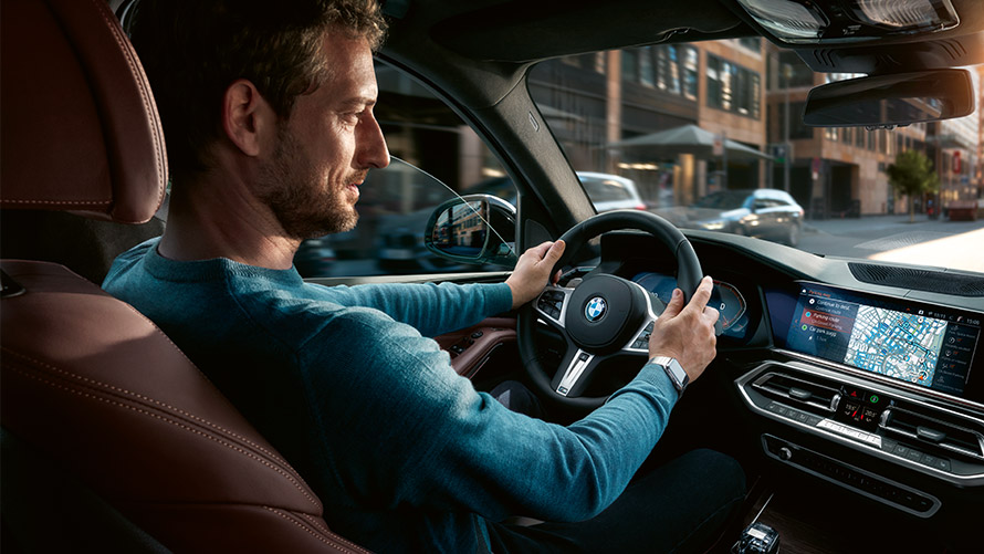 Asistent Parking Place Assistant Muž používající asistent Parking Place Assistant na displeji BMW