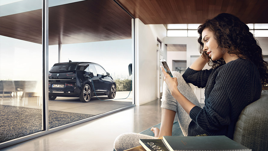 Služba digitálního nabíjeni Žena doma na chytrém telefonu používá funkci Služba digitálního nabíjení pro její BMW i3