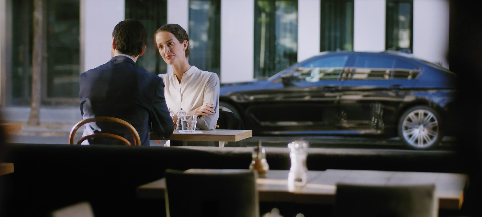 BMW Corporate Aftersales: Muž a žena sedí v kavárně BMW Corporate Aftersales: Muž a žena sedí v kavárně, v pozadí stojí BMW