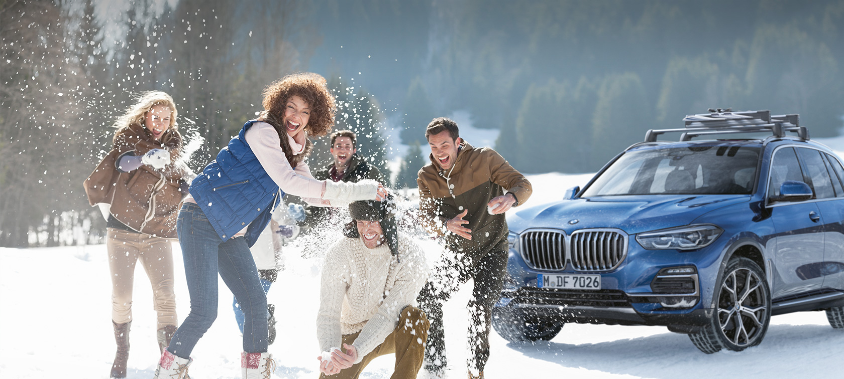 BMW Originální příslušenství a BMW Servis pro podzim a zimu Žena a muž se smějí ve sněhu před BMW