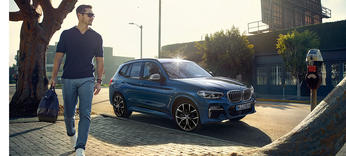 Muž ve slunečních brýlích před modrým BMW Muž ve slunečních brýlích před modrým BMW
