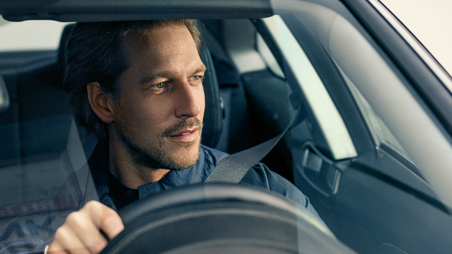 Muž řídící BMW Muž řídící BMW se dívá přes čelní sklo