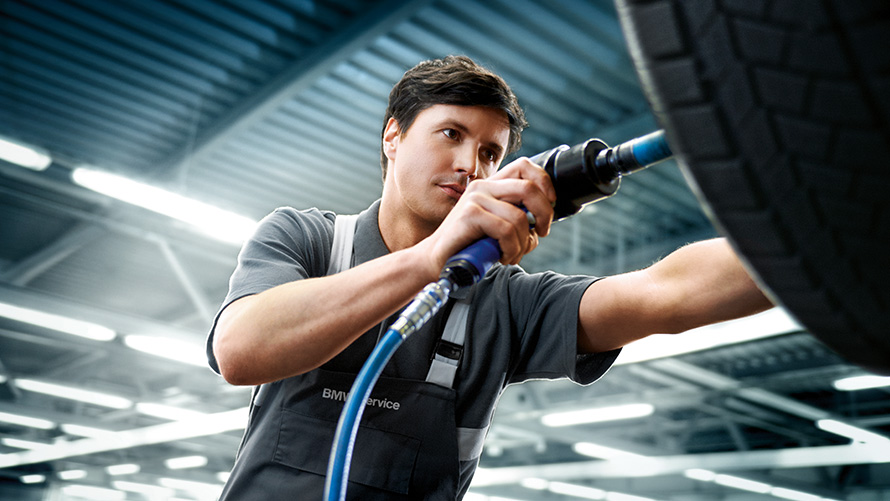 BMW nabídky, servis kol BMW letní nabídky, servis kol, zaměstnanec BMW servisu opravuje BMW