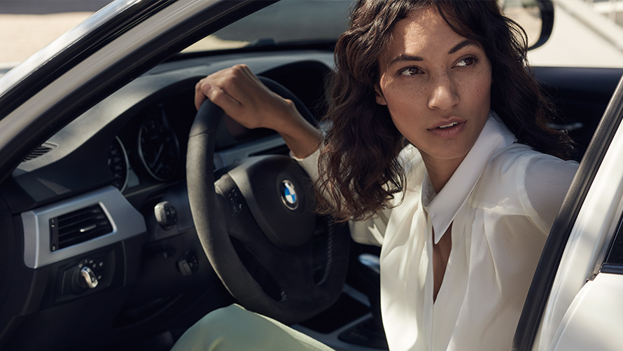 BMW Value Service Zákaznice BMW Servisu se dívá přes otevřené dveře jejího BMW