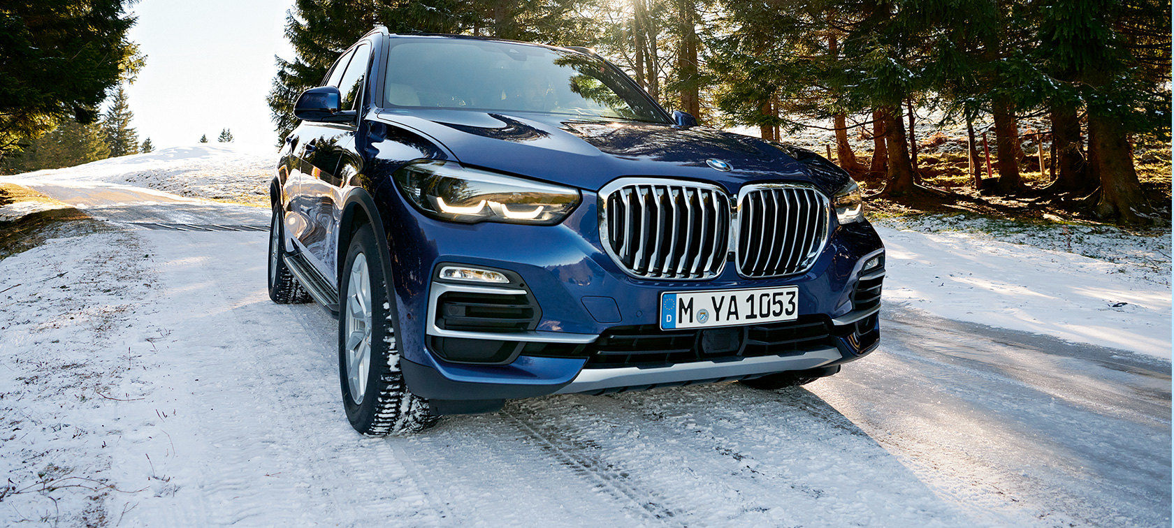 BMW Originální příslušenství pro podzim a zimu Tříčtvrteční pohled na modré BMW X3 na zasněžené silnici