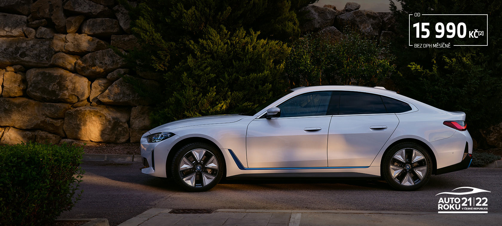 BMW i4 eDrive40 G26 2021 Mineral White tř&iacute;čtvrtečn&iacute; pohled zepředu stoj&iacute;c&iacute; před jezerem s kopcem v pozad&iacute;