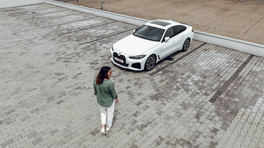Žena jde směrem k BMW i4, ale dívá se na pravou stranu. Žena jde směrem k BMW i4, ale dívá se na pravou stranu.