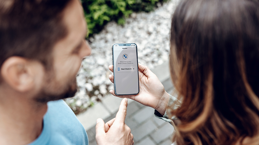 Muž ukazuje na displej telefonu. Na displeji je logo BMW. Muž ukazuje na displej telefonu. Na displeji je logo BMW.