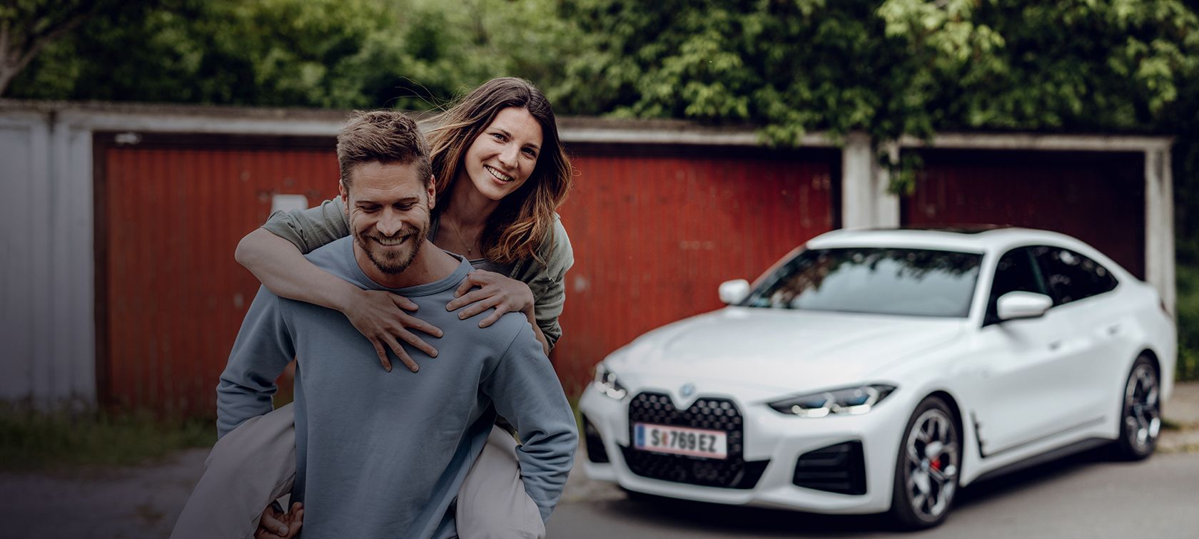 Smějící se muž odchází od BMW i4 a za ním jde usměvavá žena. Smějící se muž odchází od BMW i4 a za ním jde usměvavá žena.
