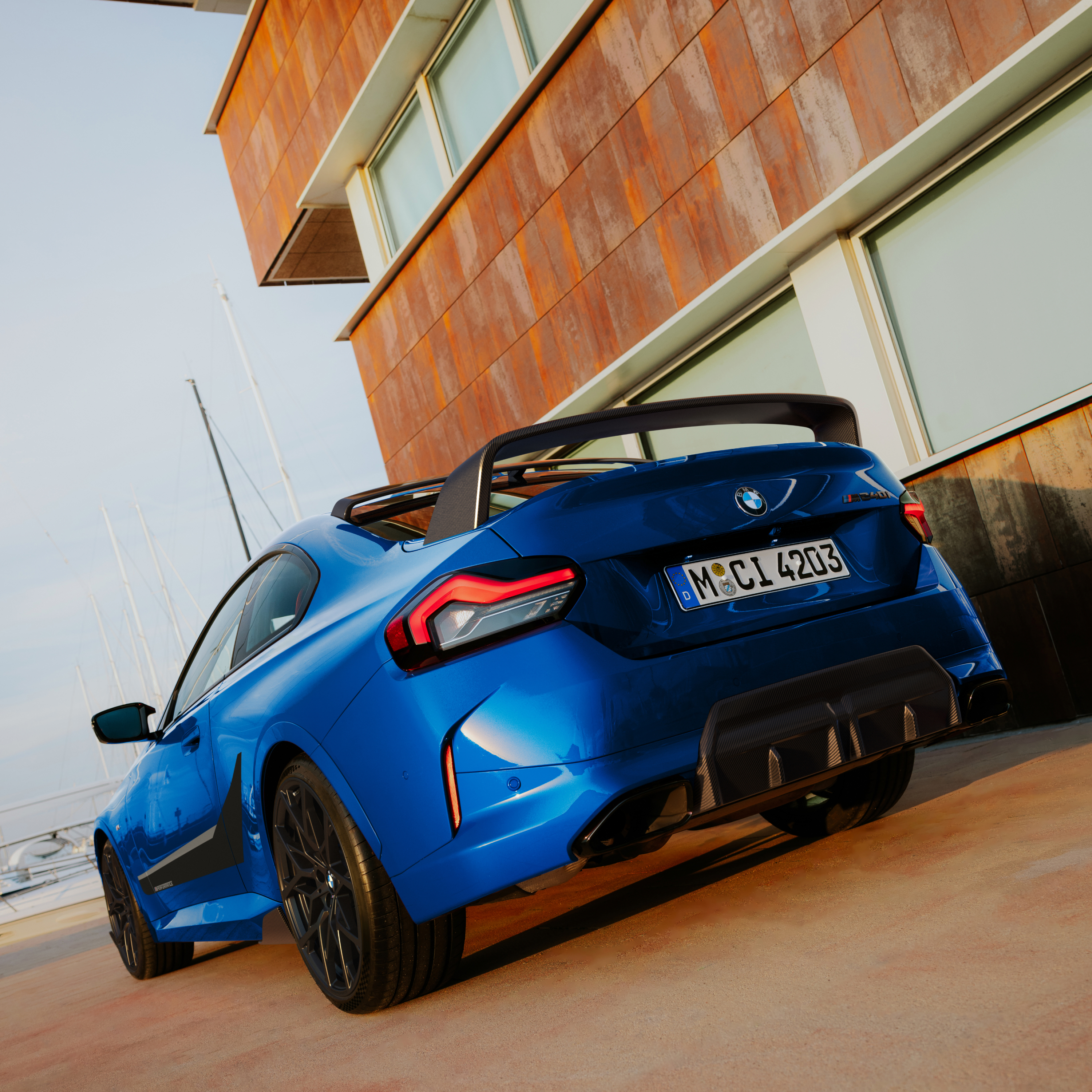 BMW se zadním spoilerem M Performance zaparkované před domem